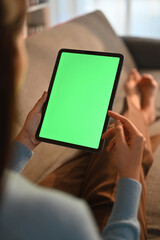 Close up view of casual young woman using digital tablet on couch at home. Green screen for montage your graphic display