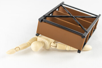 玩具の家具とデッサン人形。家具の下敷きになるイメージ