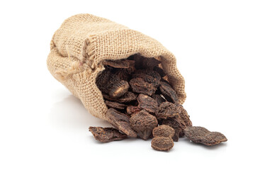 Close-up of Dry Shikakai (Acacia concinna) fruits, spilled out from a laying jute bag over white background.