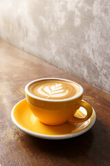 Close up white coffee cup with heart shape latte art on wood tab