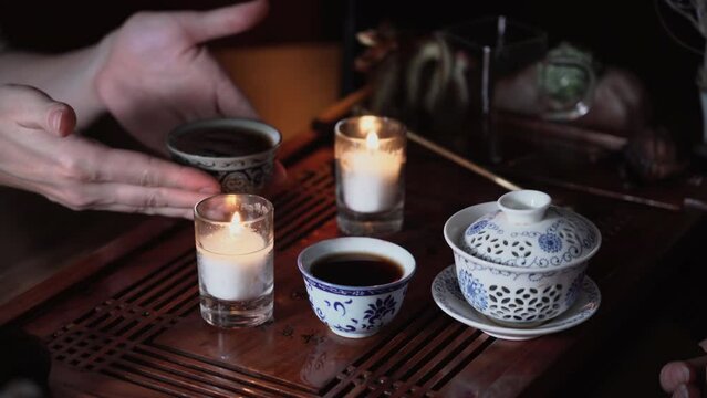 woman chatting over cup of hot puero during a tea ceremony while sitting at a table indoors, hands close-up
