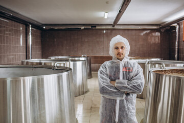A handsome brewer examines beer from tanks in a brewery