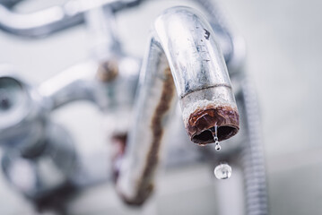 Close up of old tap in rust, one drop of water falling from the faucet, toned photo. Problem of low...