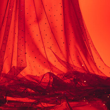 Dark elegant wallpaper made of red tulle fabric with sequins.  Aesthetic fashion, passion and love background.