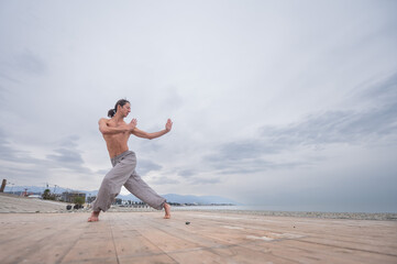 Caucasian man practices martial arts outdoors. balance and meditation.