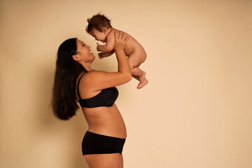 Asian woman in underwear holding a toddler above head