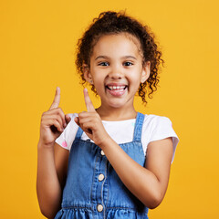 Portrait, pointing up and girl with smile, branding development and happiness against a studio background. Face, female child and young person gesture for space, direction and showing with choice
