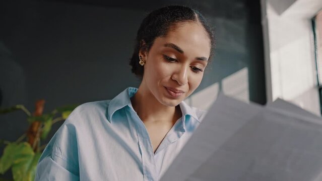Close-up successful ethnic woman reading contract, rejoicing in conclusion of deal, winning tender