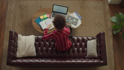 Top view of joyful African American young female reading college decision notification letter, celebrating university admission with winning gesture, expressing excitement and happiness.