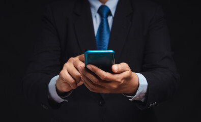 Businessman in a suit using a smartphone while standing on a black background