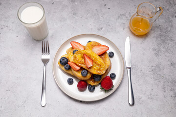 Flatly Torrijas, French Toast Made Of Sliced Bread, Served With Orange Topping, Glaze, Fresh Blueberries, Strawberry. Glass Of Milk On Granite Table With Fork, Knife. Dessert On breakfast. Horizontal