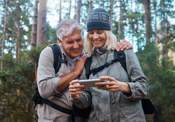 Phone, hiking and happy senior people in nature with network, social media or video streaming in forest. Mature couple of friends trekking or travel in woods with funny meme, smartphone or mobile app