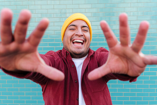 Cheerful man stop gesturing in front of turquoise brick wall
