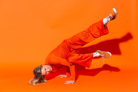 Woman breakdancing against orange background