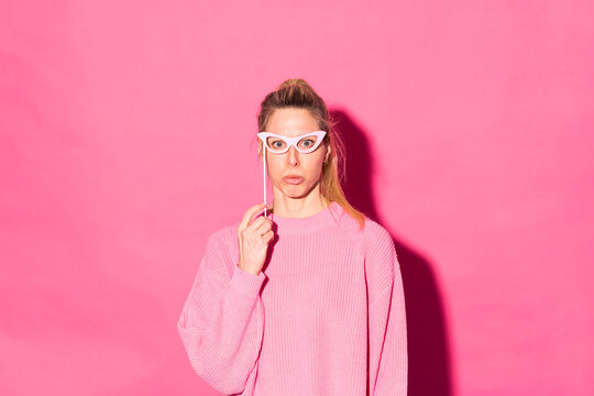 Woman with party glasses standing against pink background