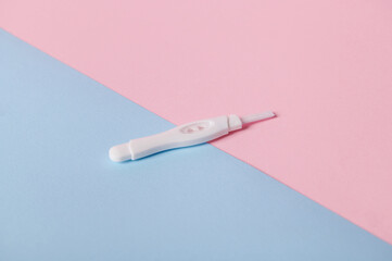 View from above of inkjet pregnancy test with two bars, showing positive reaction between female urine and chg hormone, isolated bicolor pink and blue background. Women's health and Planning maternity