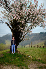 Foto scattata ad una ragazza in posa vicino ad un mandorlo in fiore.