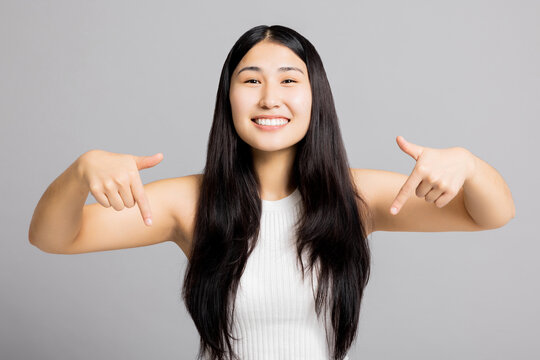 Portrait of adorable delighetd asian woman pointing index finger herself impressed she choose news wear good look white asic casua t-shirt isolated over grey background.