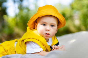 Cute baby lying on a blanket on the grass outdoors in summer. Happy and healthy childhood concept