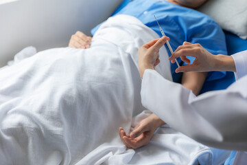 Close-up of doctor handing drops to sick male patient in hospital bed.