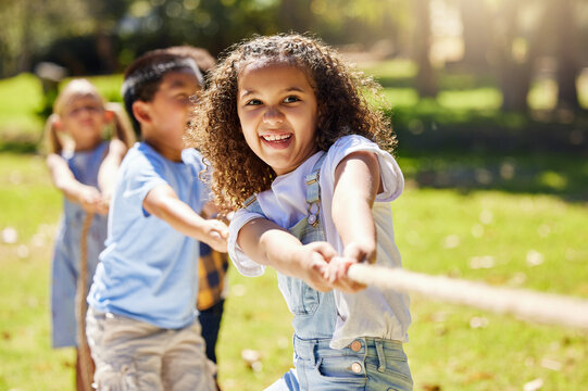 Funny, games and children playing tug of war together outdoor in a park or playground during summer. Friends, diversity and kids pulling a rope while having fun or bonding in a garden on a sunny day