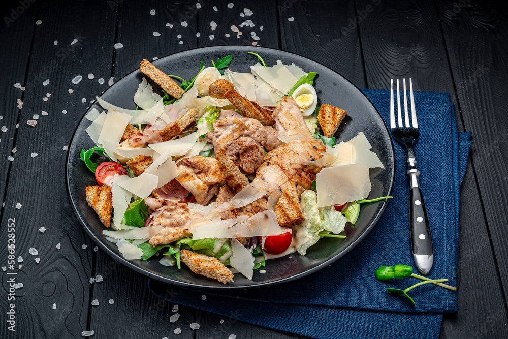 Poster fresh caesar salad in white plate on dark wooden table. top view.