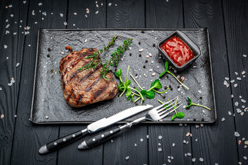 Beef rump steak on black stone table.