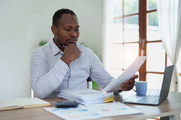 Fototapeta premium middle aged man American African using computer laptop with planning working on financial document, tax, exchange, accounting and Financial advisor