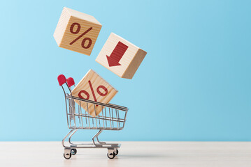 Shopping cart with cubes falling into it with percent symbols and down arrow