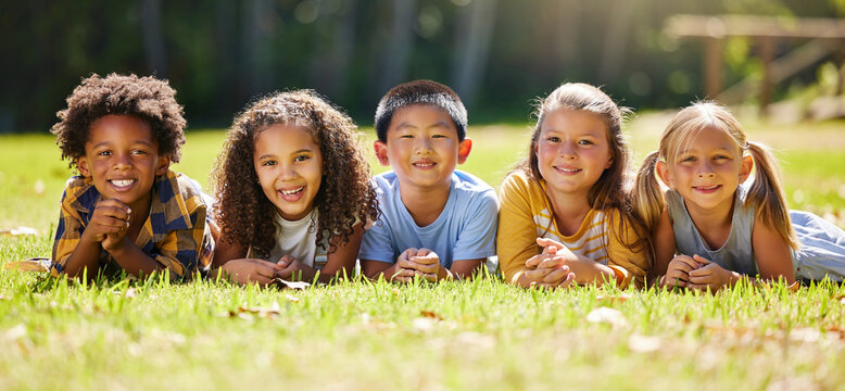Portrait, diversity and children on grass, friends and summer break with smile, chilling and relax. Face, kids and young group in park, multiracial and fun on vacation, weekend and joyful together