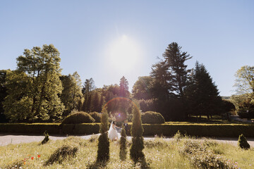 the bride and groom run against the background of the castle in spring flowers and beautiful light. An incredible couple