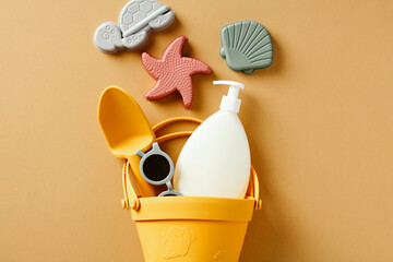 Set of kids sand molds and sunblock lotion on beige background. Summer vacation concept.