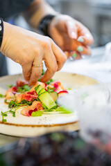 Chef cooking Green salad with salmon, cucumbers, lettuce, spices, caviar on restaurant kitchen