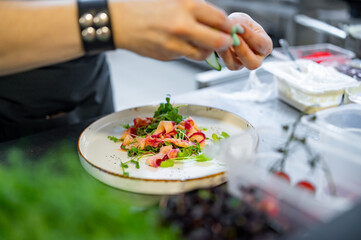 Chef cooking Green salad with salmon, cucumbers, lettuce, spices, caviar on restaurant kitchen