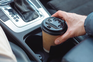 Man take Paper Cup from cup holder in car. Hot drink to take away with you on the road.