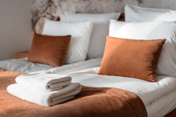 cozy bedroom with clean bath towels, cushions and bedding
