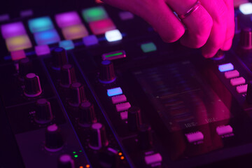 Hands of a DJ creating and regulating music on dj console mixer at club concert