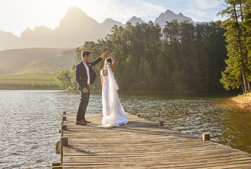 Married, dance and a couple on a pier over a lake in nature with a forest in the background after a...