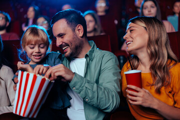 Happy parents with child in cinema.