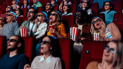 Excited people watching movie in 3D theater,