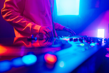 Hands of a DJ creating and regulating music on dj console mixer at club concert