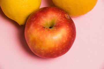 Apple and lemons on a pink background close-up. Delicious fruits on a bright background.