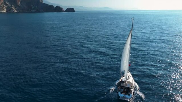 One yacht with white sail in open sea. A nice luxury yacht with sails floating on the blue waves.