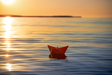 toy paper origami ship floats on water, travel and freedom concept