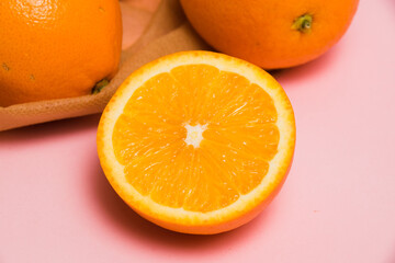 Juicy oranges in a reusable bag for fruits and vegetables on a pink background. Concept of earth day, zero waste and recycling.
