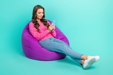 Full length photo of lovely girl sitting bean bag use iphone write instagram facebook post empty...