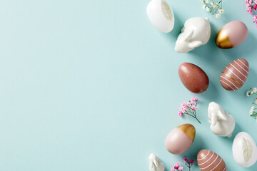 Happy Easter greeting card template. Colorful Easter eggs, minimalist flowers, decorative rabbits on pastel blue background. Flat lay, top view.