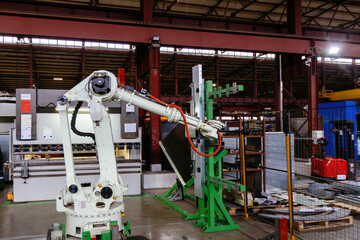 Robotic arm working with metal sheet at metalworking factory