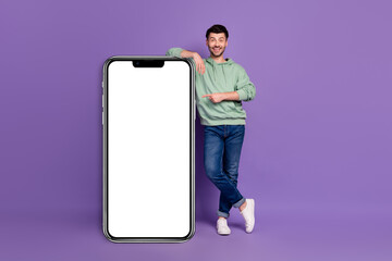 Full length photo of nice young man lean point vertical device screen wear trendy gray outfit isolated on violet color background