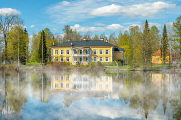 Fototapeta premium Kouvola, Finland - May 16, 2019: Beautiful wooden Rabbelugn Manor - Takamaan Kartano in fog.